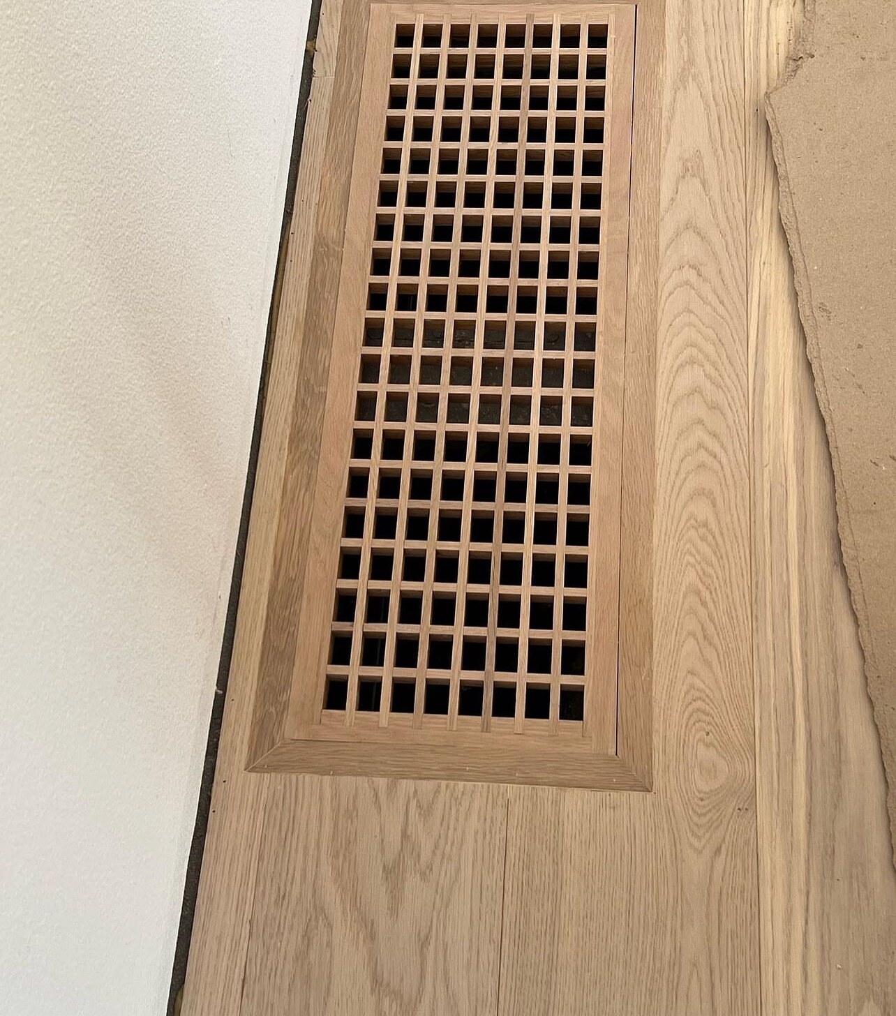 A custom white-oak floor vent inlaid flush with the plank, level with the floor