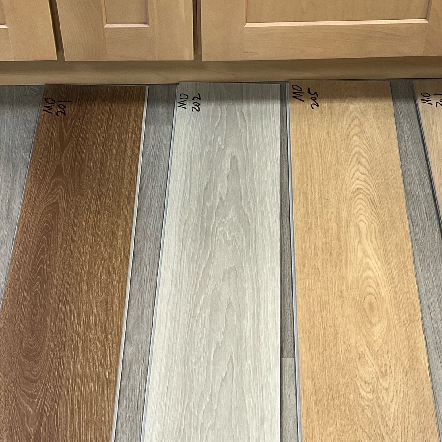 Plank samples laid out for a client in front of the cabinets they'll live with