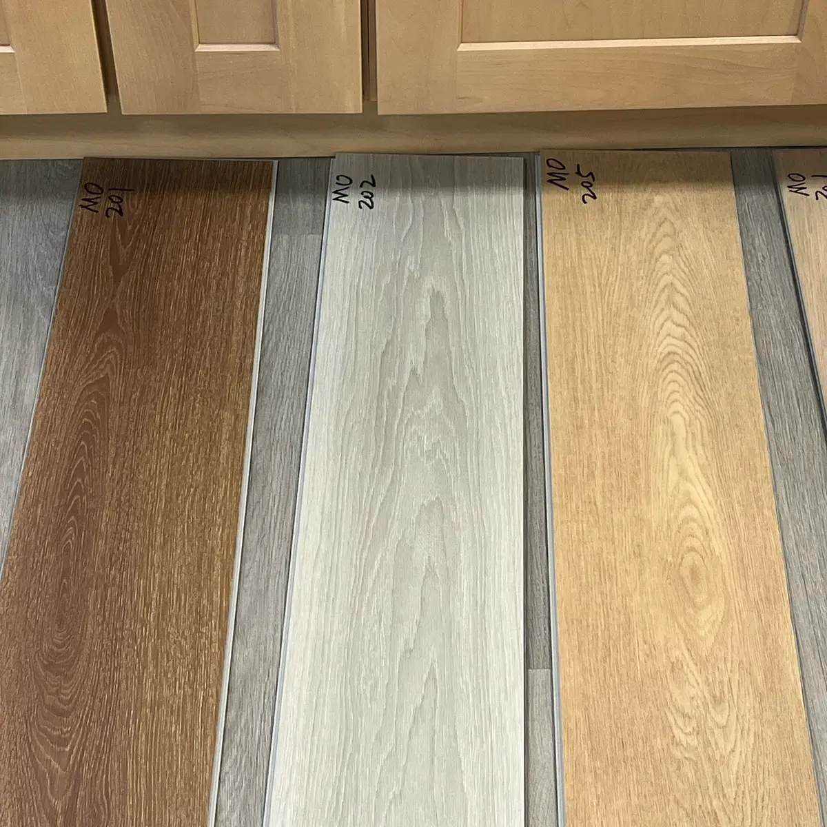 Plank samples laid out for a client in front of the cabinets they'll live with